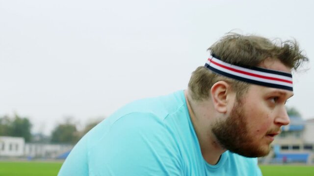 Good looking man obese prepares to start run in the stadium outside he wearing sports clothes he are at the starting line