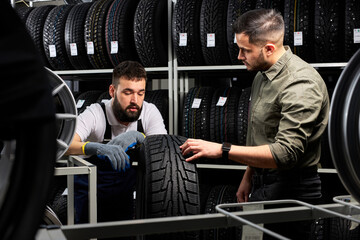 mechanic and client checking tires in store, having conversation in shop, customer is going to make...