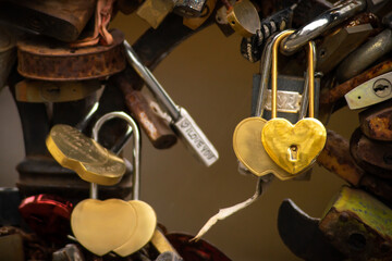 Close-up of golden, heart shaped, wedding padlocks hanging on bridge fence.