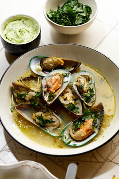 Cooked kiwi green mussels with wine, garlic and parsley served with baguette and butter with herbs