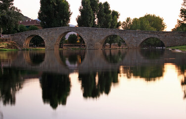 Fototapeta na wymiar Stone bridge, river with ducks and reflection