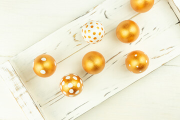 Easter festive decoration. Top view of easter eggs colored with golden paint on white wooden tray. Various dotted designs.