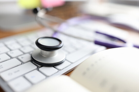 Stethoscope lying on computer keyboard in doctors office closeup