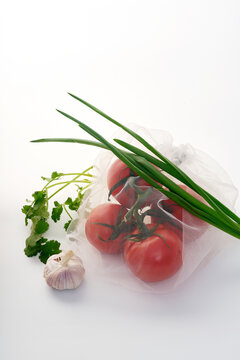 Still life with tomatoes in net mesh bag back lit on white background