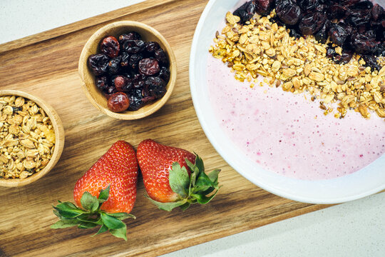 From above nutritious oatmeal and dried berries in bowl with yogurt served on table with fresh strawberries in bright kitchen
