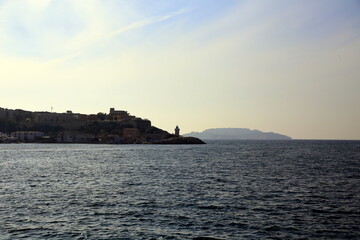 Obraz premium View of the distant lighthouse in the sea and the island against the light