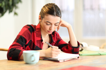 Student studying taking notes at home