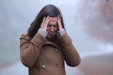 Sad woman in winter complaining alone in a park