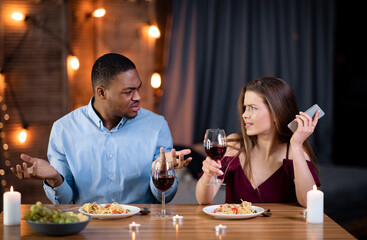 Annoyed Black Guy Arguing With His Girlfriend Busy With Cellphone On Date