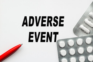 Text ADVERSE EVENT, on white background. There are various pills and vitamins around. Medical...