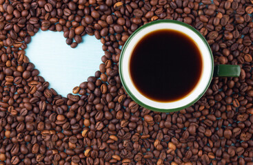 cup of coffee on the table next to the heart painted in coffee beans