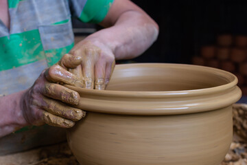 Wet and muddy hands of a craftsman shaping a clay vase on a pottery wheel. Artisan from Ráquira, Colombia. Shallow depth of field