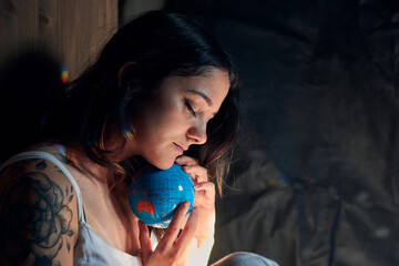 Side view of serene female with closed eyes embracing Earth globe showing concept of saving planet