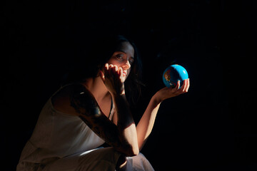 Side view of serene female holding Earth globe showing concept of saving planet looking at camera