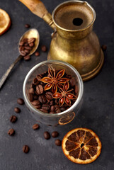 Coffee with coffee beans, dry orange and anise on black background. Coffe with spices. Top view.