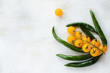 Green chilli peppers and colorful cherry tomatoes on the white background