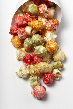 High angle of colorful tasty popcorn in paper cone placed on white background in studio