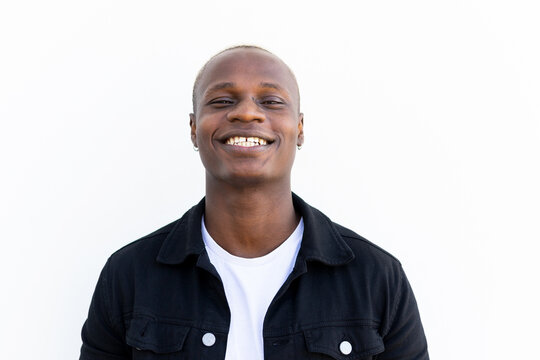 Satisfied African American male in casual outfit smiling and looking at camera on white background