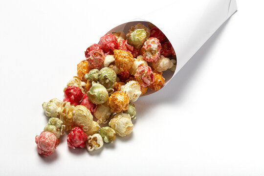 High angle of colorful tasty popcorn in paper cone placed on white background in studio