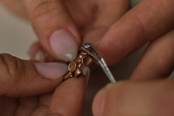 Macro shot. Craft jewelery making. Ring repairing. Putting the diamond on the ring. Desktop for craft jewellery making with professional tools.