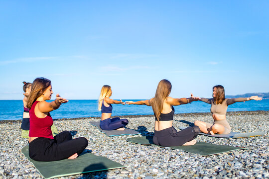 group of five women practicing yoga assans in morning beach . only girls session