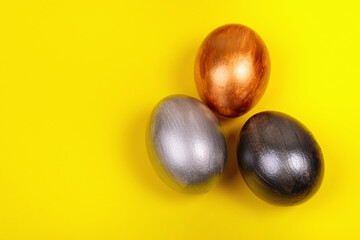 Multi-colored eggs on a uniform yellow background with place for text.