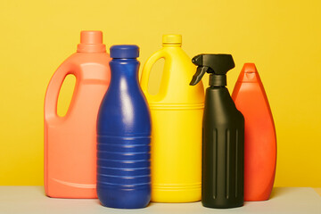 Set of colorful assorted plastic containers from liquid detergents placed in row on yellow background in studio
