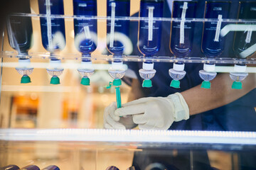 Unrecognizable cosmetologist in gloves filling syringe with chemical liquid for skin care procedure in modern beauty clinic