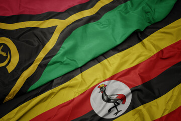 waving colorful flag of uganda and national flag of Vanuatu .