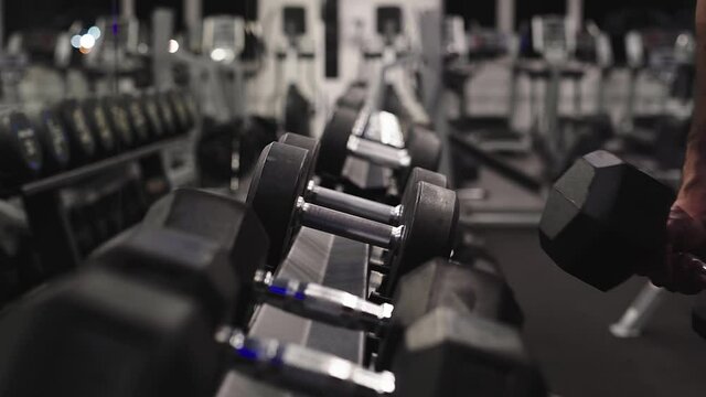 Closeup of hand grabbing and lifting kilograms at workout studio.