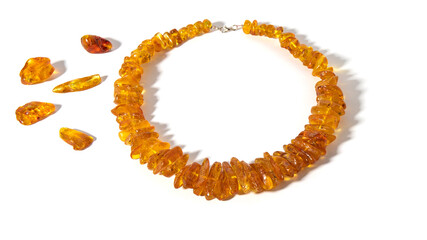 Obraz premium Sparkling transparent orange old Baltic amber necklace on a white background. Isolated amber jewelry and amber stones. Ancient amber is healing, powers, strength, love, protection and amulet. 