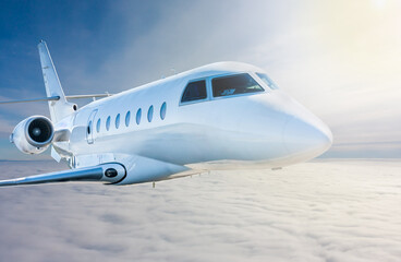 Fototapeta na wymiar White modern luxury private jet flies in the air above the clouds. Close-up view business airplane