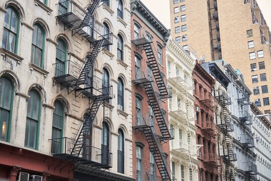 From below of exterior of old shabby apartment buildings with metal ladders in New York