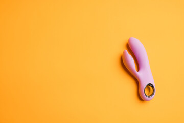 Pink massager for sex on an orange background. Vibrator for masturbation. Dildo for vaginal stimulation and clitoral stimulation. Image for a sex shop. Sex toys for adults. Massager for the clitoris