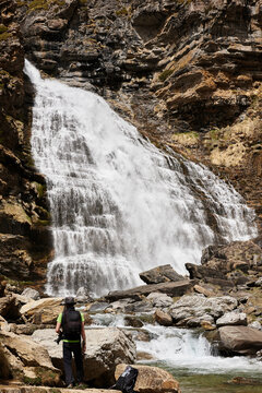 Traveler in scenic view of waterfall in highland area in Pyrenees mountains on sunny day in Ordesa Valley