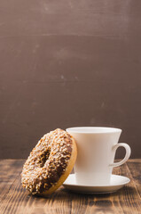 White cup of black coffee and donut with nuts.