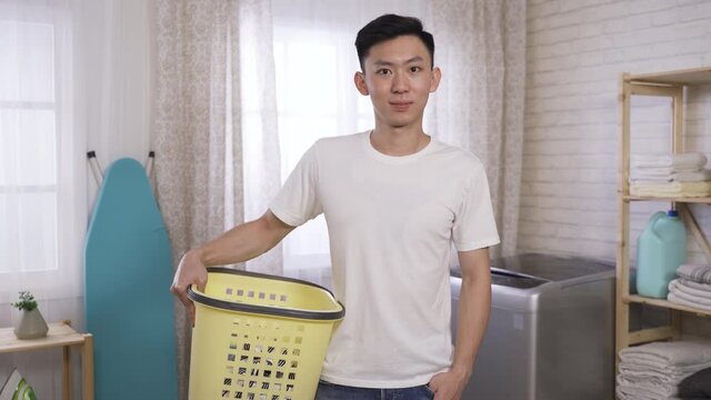 image of nice guy smiling at camera holding laundry basket and hand in pants pocket.