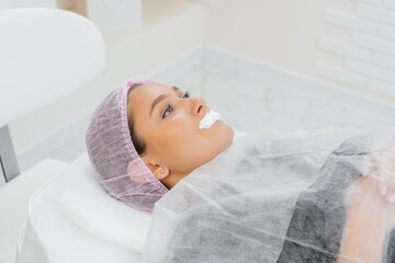 Moisturizing the lips during a cosmetic procedure for a young girl. Cosmetology