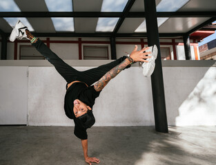 Full body of energetic young man doing acrobatic handstand while performing break dance