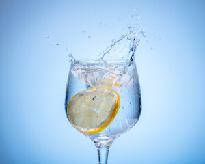 glass of water with lemon droped in and splash