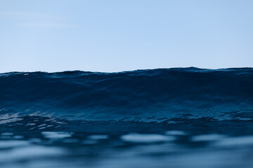 Powerful foamy sea waves rolling and splashing over water surface against cloudy blue sky
