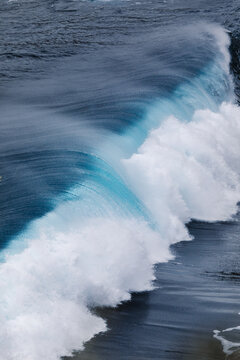 Powerful foamy sea waves rolling and splashing over water surface against cloudy blue sky