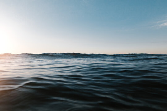 Tranquil seascape of endless ocean with calm rippled water reflecting sunlight under blue sky with clouds at sundown time
