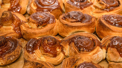 Homemade cinnamon buns with spices and caramel on parchment paper.