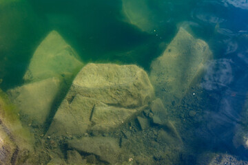 The waters of the basalt lake, the stones in the lake are covered with algae, clear and pure water.