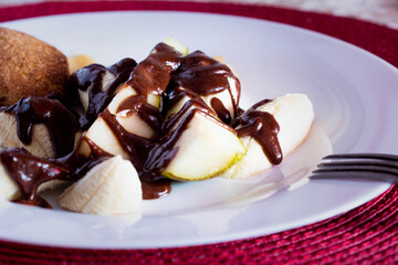 Banana pear dessert on white plate poured with chocolate sauce. Vegetarian salad.