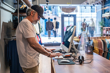 Side view of clothing store owner checking sales on computer