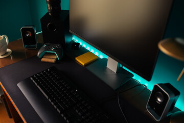 Modern stylish black gaming computer with keyboard and speakers placed on table near joystick lamp and stationery