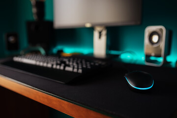 Modern stylish black gaming computer with keyboard and speakers placed on table near joystick lamp and stationery