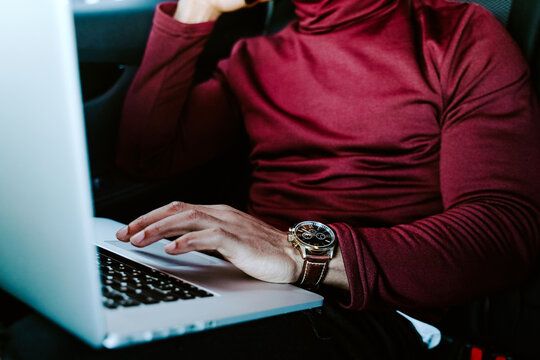Unrecognizable crop African American male entrepreneur using touchpad and browsing laptop while working on project remotely